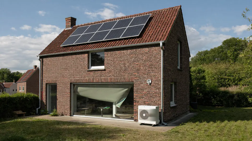 Woning met zonnepanelen op het dak en een buitenunit aan de zijgevel